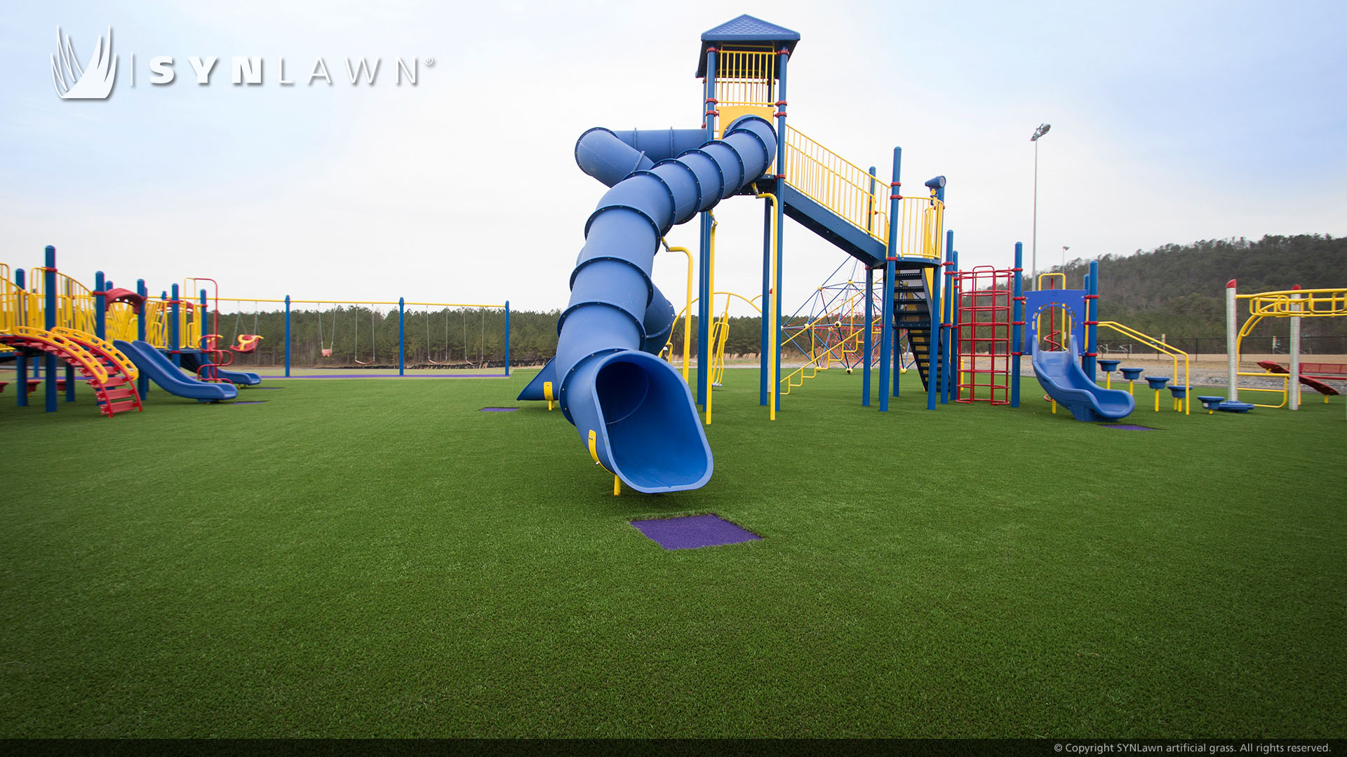 Blue slide and jungle gym on artificial playground grass