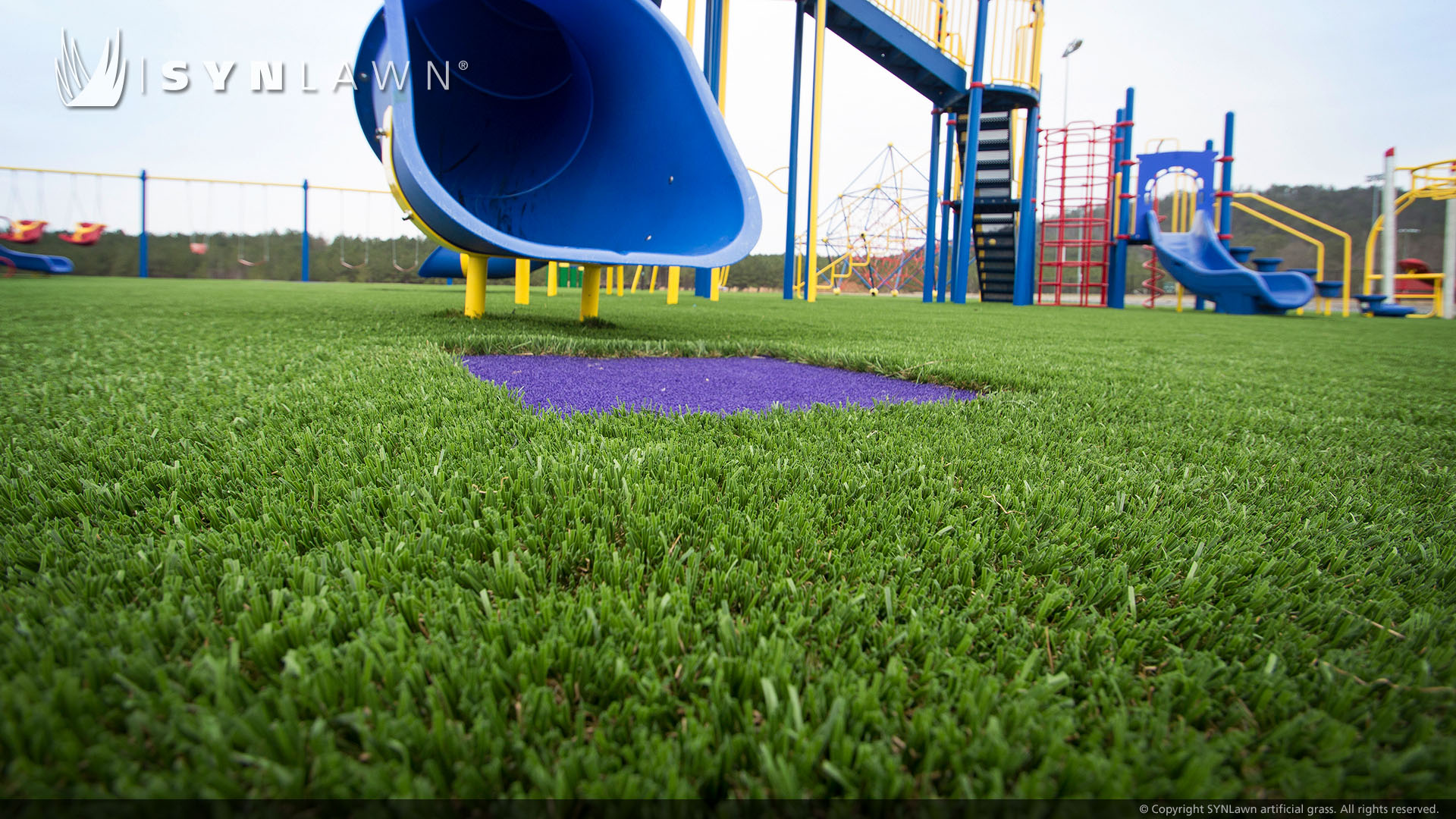 Blue slide installed on artificial playground grass