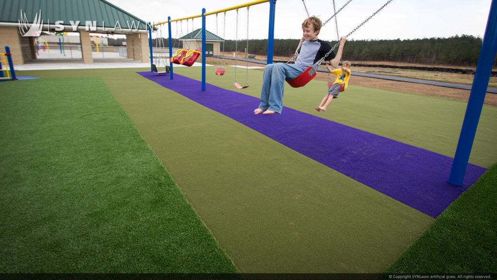 Kids playing on swingset on artificial grass