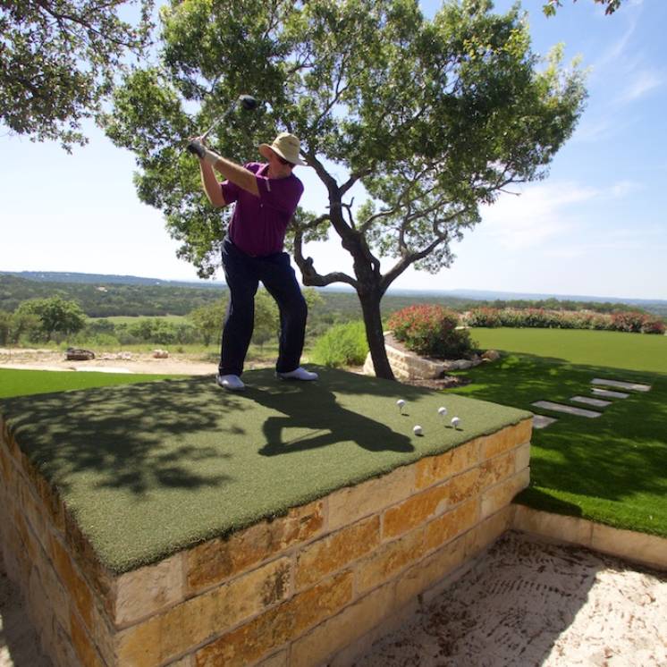 golfer practicing golf driving in private driving range with artificial grass