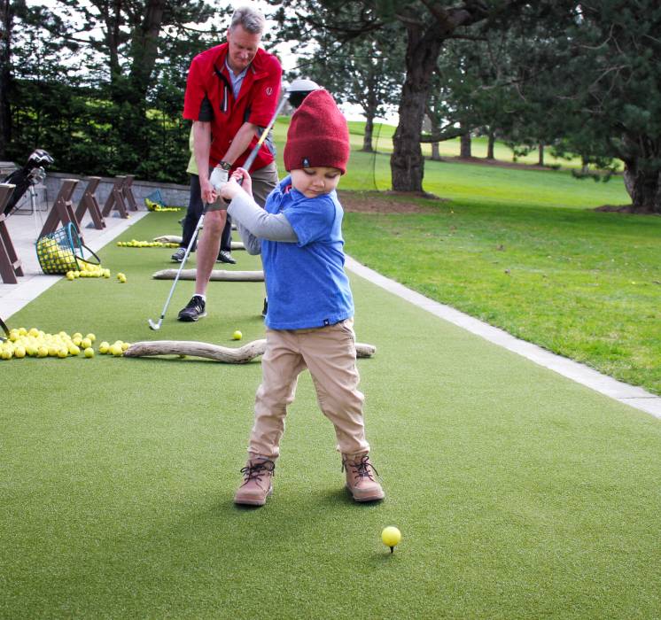 Child practicing golf driving on artificial grass