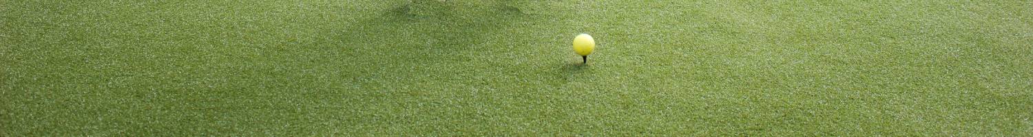 Yellow golf ball on a tee on artificial grass