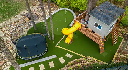Yellow slide installed on artificial playground grass